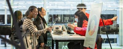 Students participate in a student health fair, interacting with one another at a table.