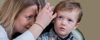 Audiologist looking child's ear