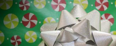 A big silver bow takes up most of the right side of the image, while yellow and red pinwheels over green make up the background.
