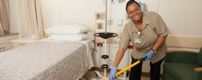 An environmental services employee cleans a patient room