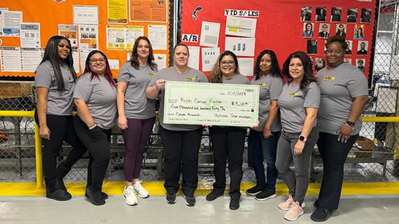 Roscoe team members showcase a novelty check representing a gift to RUSH Cancer Center after a monthlong fundraiser and matching contribution from President Jim Buik.